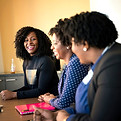 Three colleagues talking and laughing together in a conference room