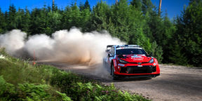 WRC car tackling a high-speed jump on the smooth gravel roads of Central Finland.