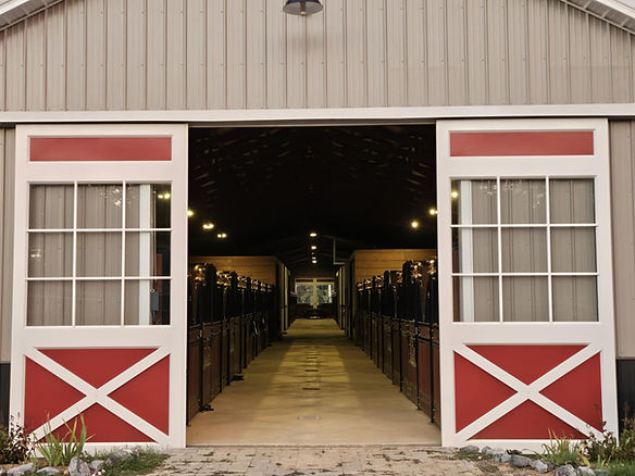 Open white and red barn doors leading into horse stalls.