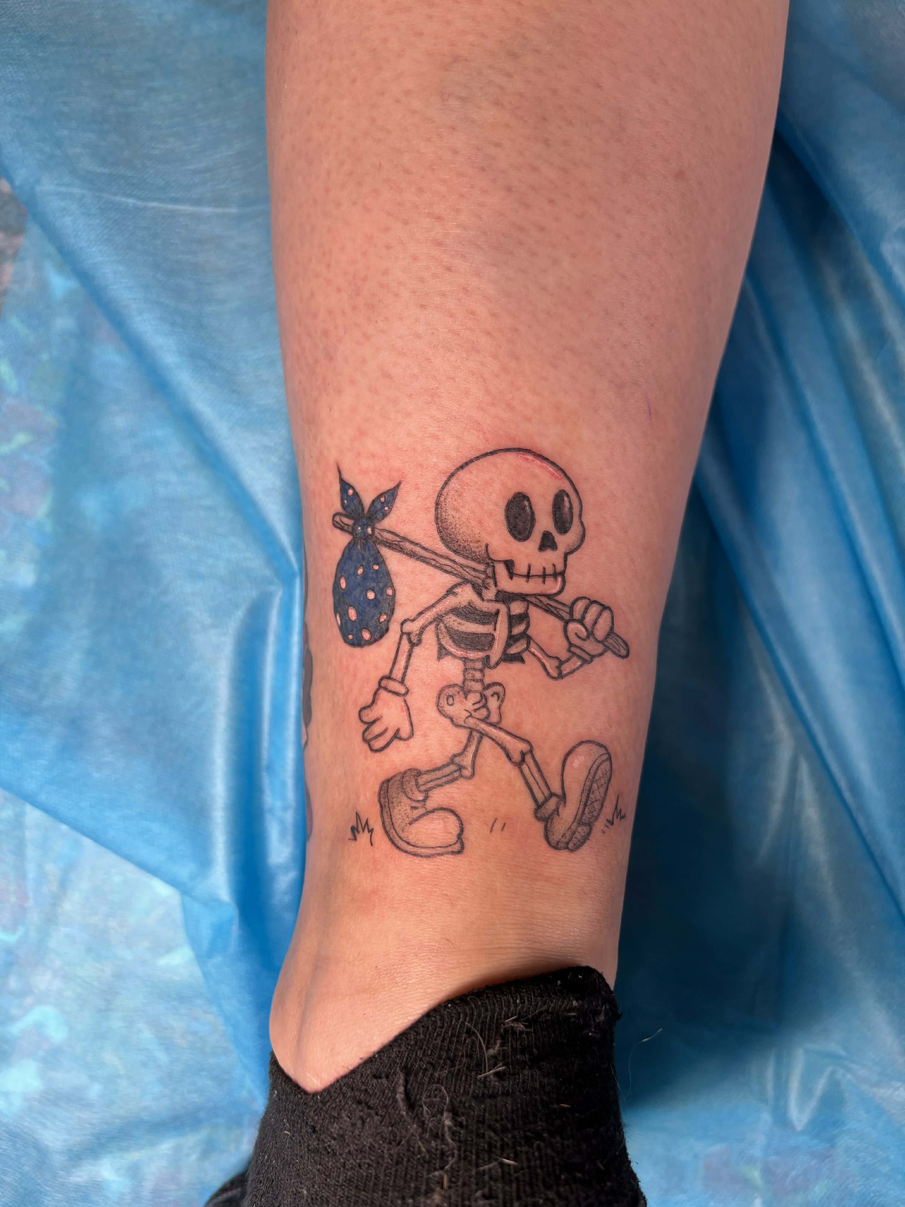 Simple black-line walking skeleton tattoo carrying a spotted bindle