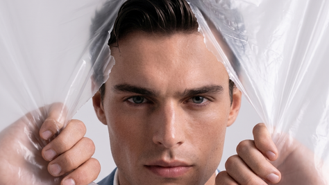 Man looking through a ripped plastic sheet