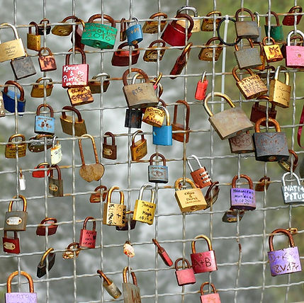 Eine Sammlung von Vorhängeschlössern, die an einem Metallzaun befestigt sind, symbolisieren die Liebe und Verbundenheit.