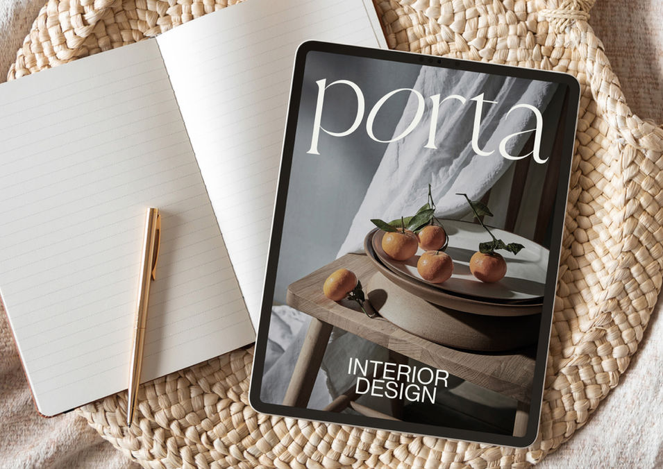 An ipad and notebook sit on top of a rattan tray. The iPad screensaver is an artistic shot of oranges on a wooden table with draped fabric behind. Text over the image reads 'Porta, Interior Design'