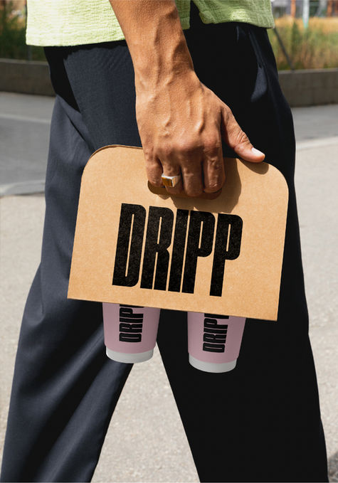 A man walking holding a cardboard coffee cup holder. The hodler has a large DRIPP logo in a bold black condensed font, with two pink coffee cups in the holder