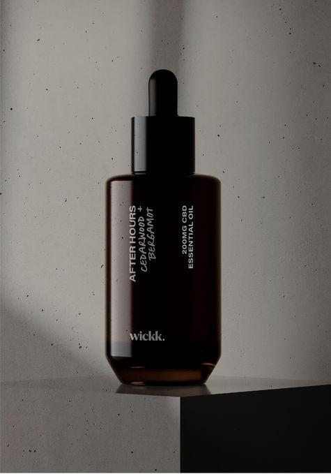 A dark brown glass dropper bottle against a studio backgdrop with shadows.