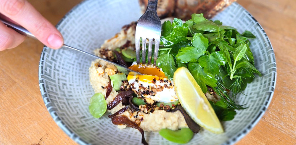 Poached egg breakfast with hummus and greens