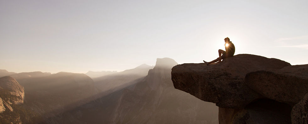a man sitting on a large rock at sunrise