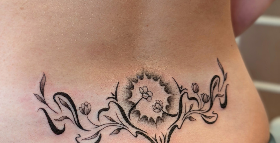lower back tatoo incorporating fine line and blackwork