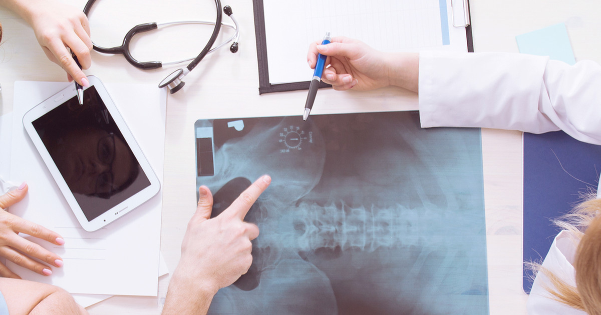 A person looking at a simple body diagram with a healthcare professional, pointing to different areas, in a calm clinical setting.