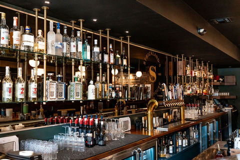 Bar filled with bottles. Bottles line the shelves behind the bar Strickland's.
