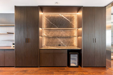 Custom storage wall with illuminated display shelves and luxury wood finishes
