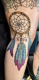 Dreamcatcher tattoo with pink and teal feathers on arm