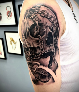Black and gray screaming skull tattoo with chains wrapping around the skull