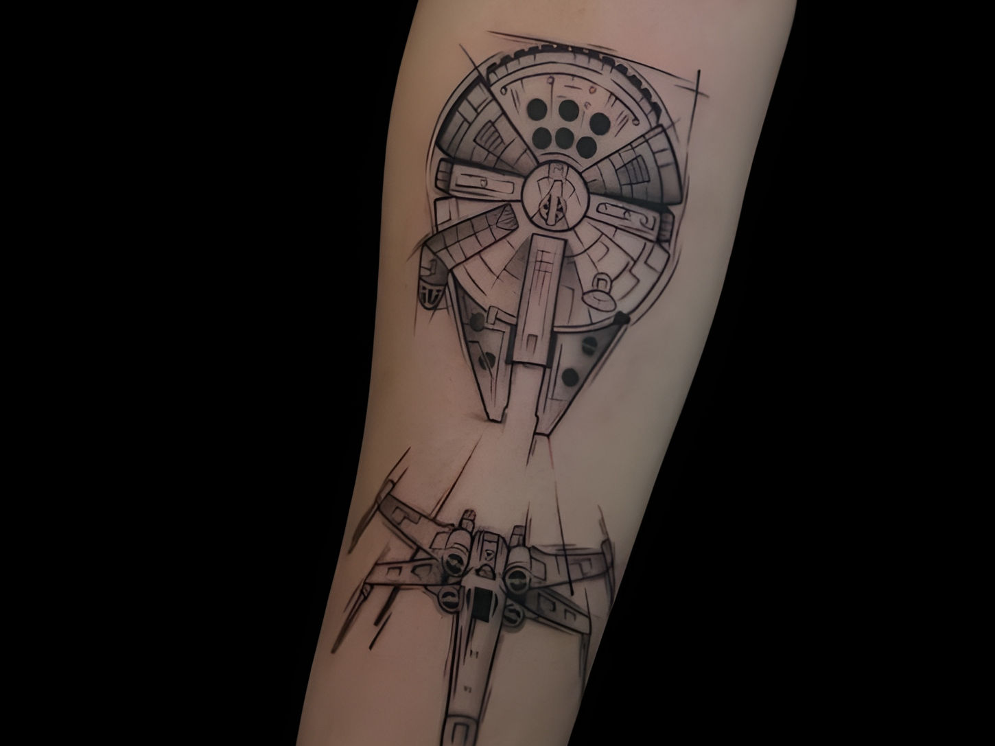 Blackwork tattoo of Millennium Falcon and X-Wing fighter on forearm.