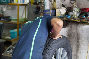 Man attaching tyre and rim into diagnostic equipment