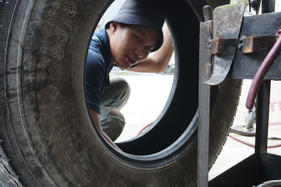 Man in hat handling truck tyre