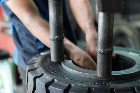 Person handling forklift tyre for pressing