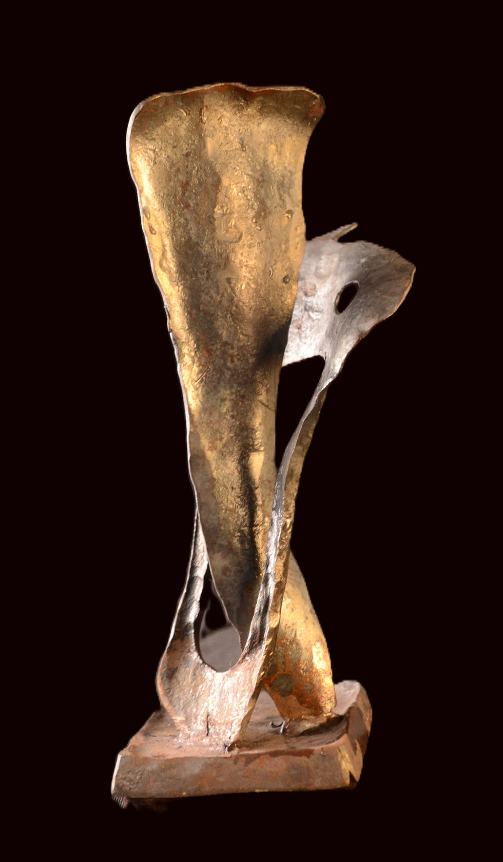 A 29 cm high hand-forged iron sculpture titled Pas de Deux, created in 2024, set against a solid black background. The abstract artwork features two vertical, stylized metal structures that twist and curve around each other, mimicking a dancing couple. The front iron form has a wide, flattened top with a textured golden-bronze and dark charcoal finish, while the secondary form wraps around it from the back. The sculpture is mounted on a small rectangular base