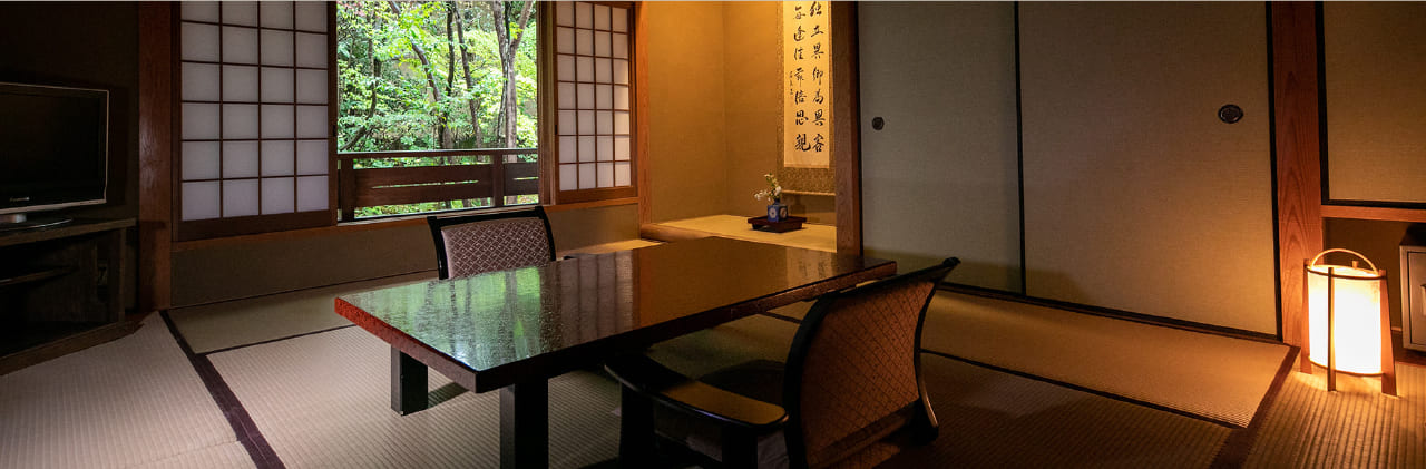 Small traditional tatami guest room and low-table dining space at Hinoharu Ryokan