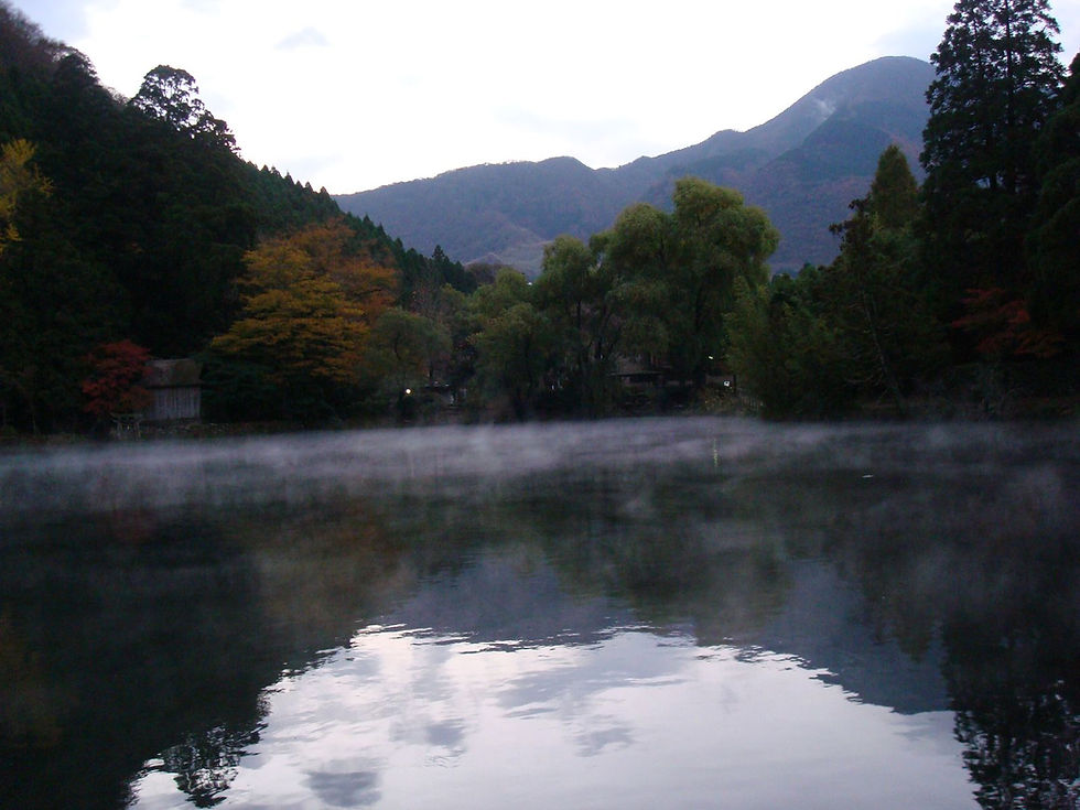 Morning mist above Lake Kinrin in Yufuin with autumn trees around the water