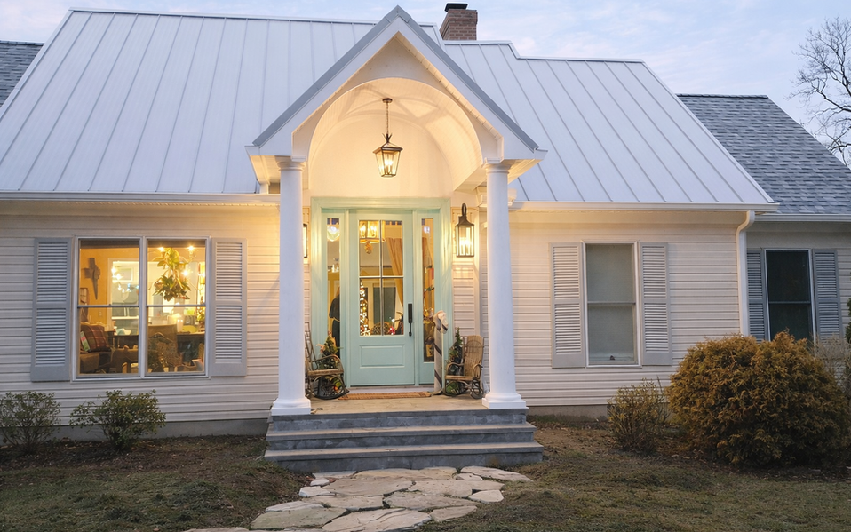 White farmhouse exterior with new portico, metal roof, and light blue front door in Easton, MD