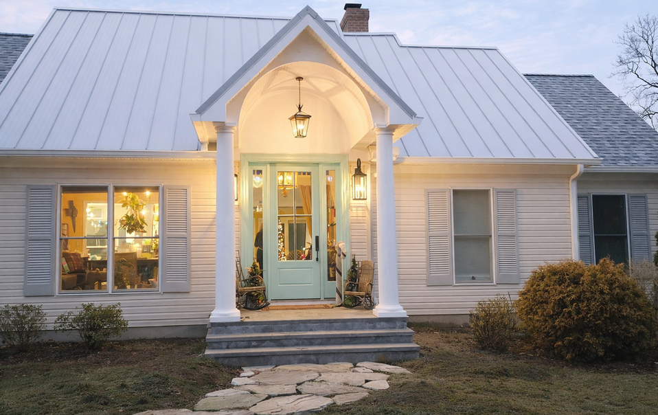 White farmhouse exterior with new portico, metal roof, and light blue front door in Easton, MD