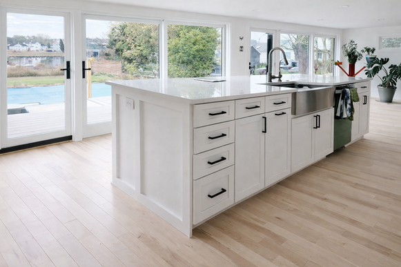 Bright modern residential kitchen with white cabinets, a large kitchen island, and hardwood flooring.