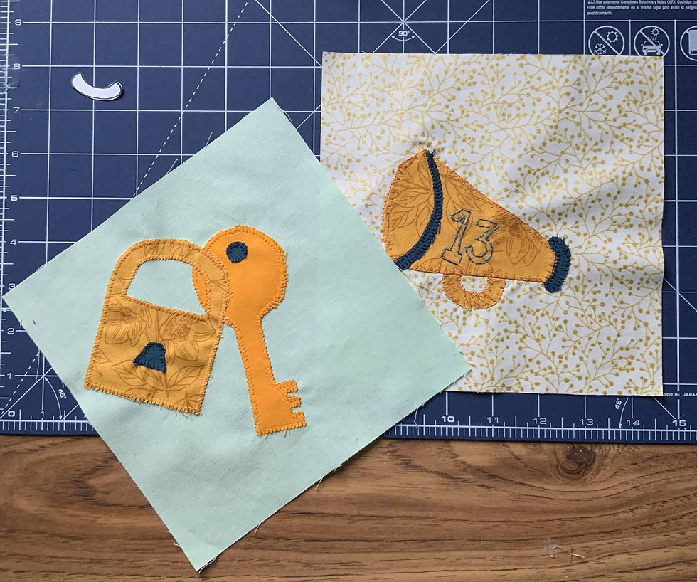 Two quilt blocks, one with a lock and key and one with a cheer cone with the number 13 embroidered on it. 