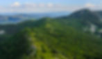 An aerial shot of Mount Thompson Rim Trail sports lush verdant plantlife and gentle rolling mountains