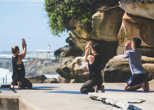 A sunny early morning Yoga class on the promenade over looking a surf beach.