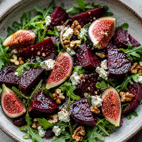 Fig, beetroot, feta, tomato salad on a bed of greens in a bowl