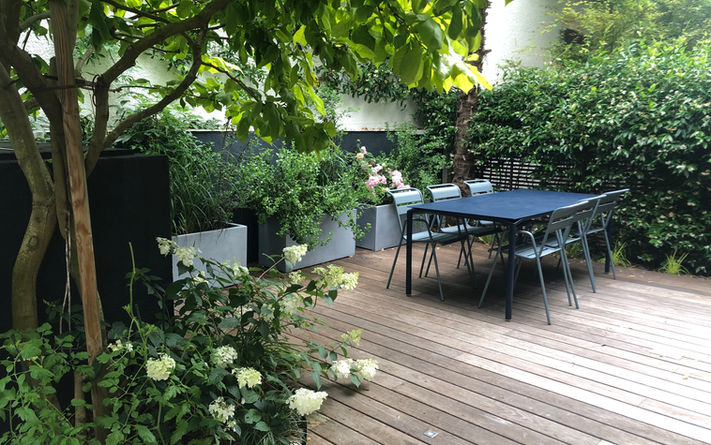 Terrasse en bois aménagée avec des massifs fleuris autour, ambiance terrasse à l'ombre, feuillages , à Boulogne Billancourt 
