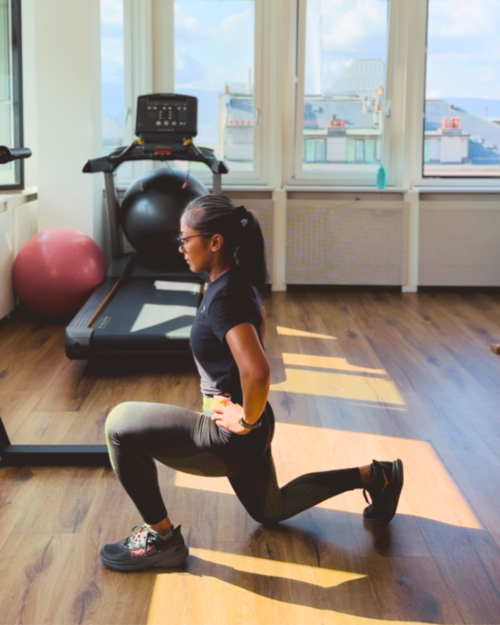Woman performing a forward lunge exercise indoors, demonstrating balance, control, and single-leg strength.