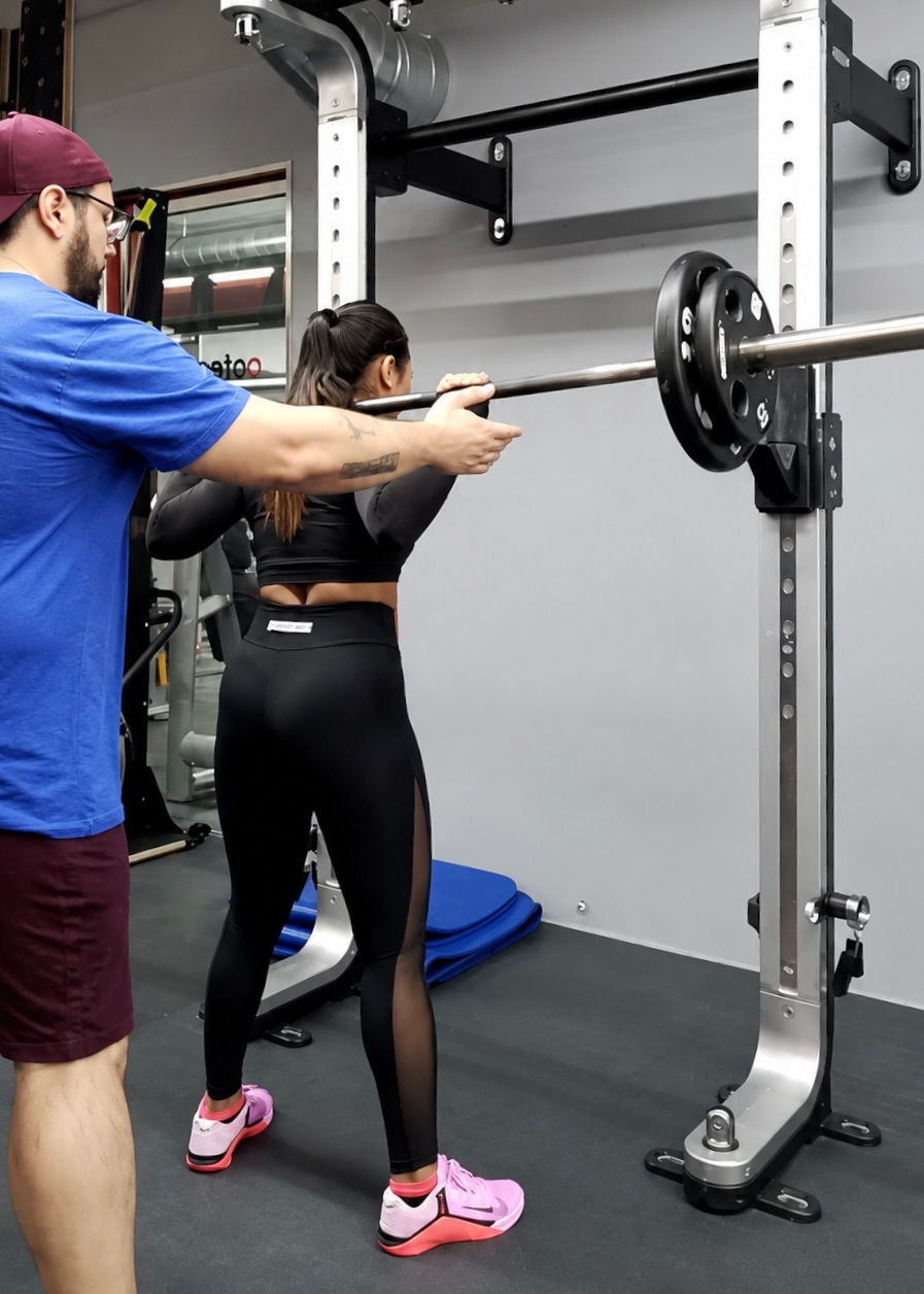 A woman preparing to squat with a trainer