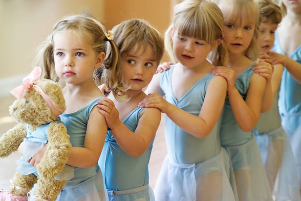 Young ballerinas in a line, holding Melody Bear