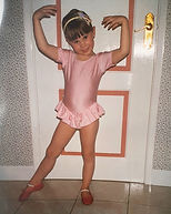 Zoé at approx. 6 years old, in a pink leotard and red ballet shoes, posing in her gran's kitchen