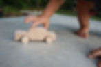 child playing with natural wooden toy car