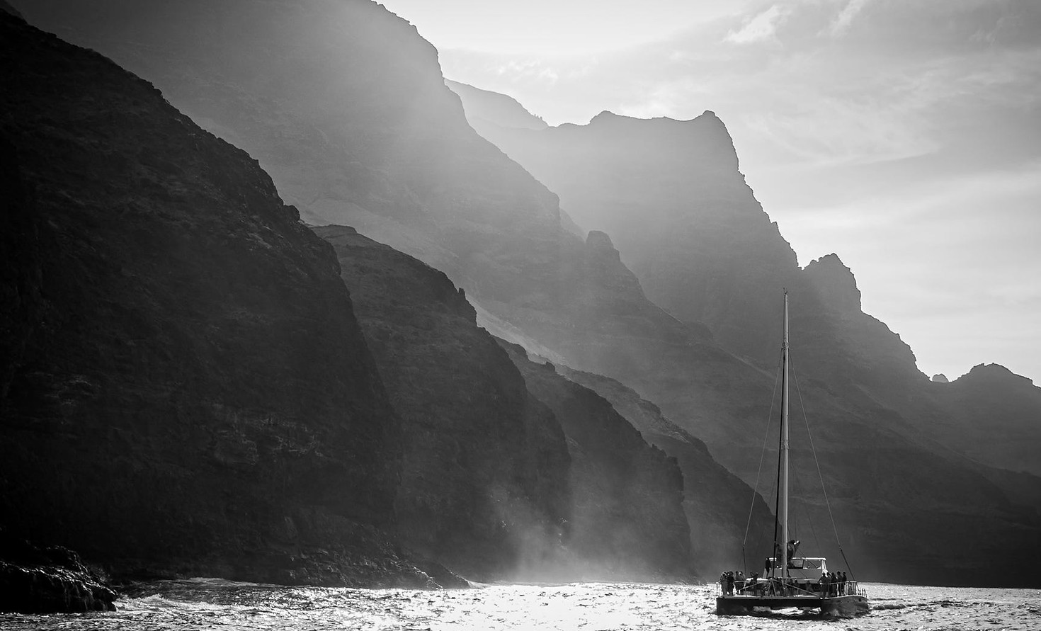 Sailboat in water below mountains in Kauai, Hawaii.
