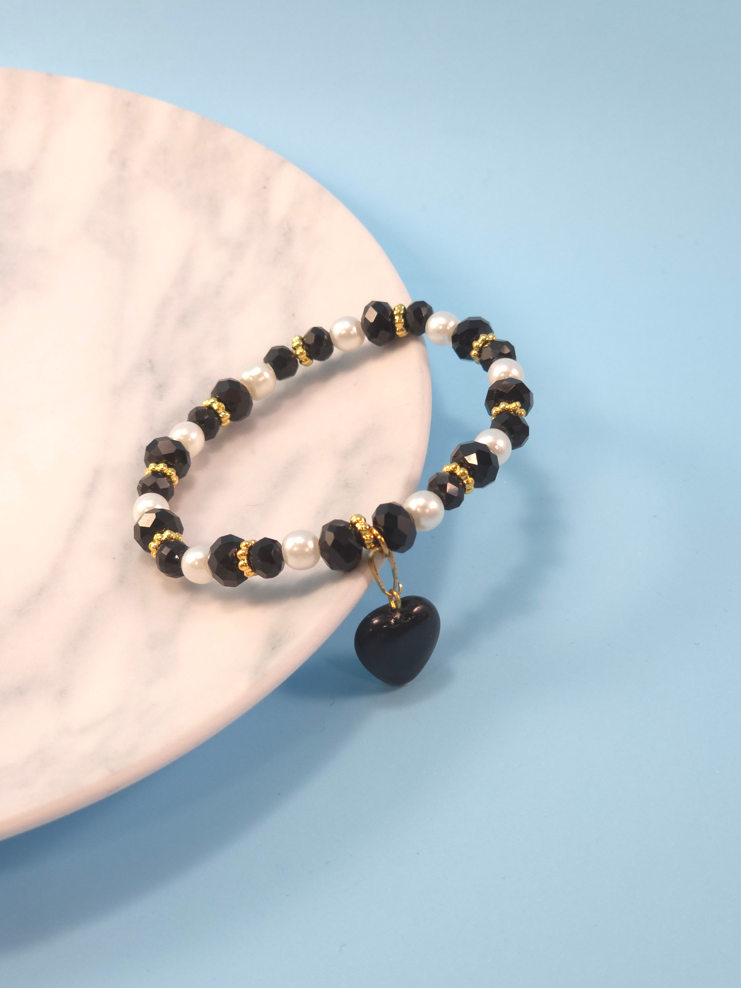 Pulsera en nylon con piedras de murano negro, perlas blancas y dije de corazón