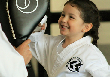 A Kombat Karate kid student with a big smile hitting karate pads