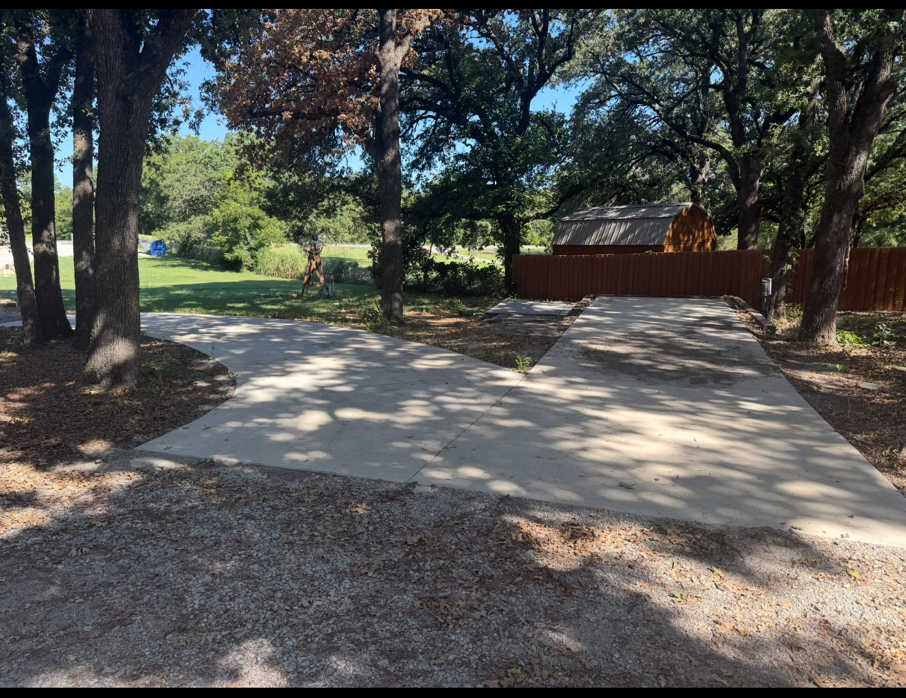 Wide angle view of a peaceful RV park with green trees and clear blue sky