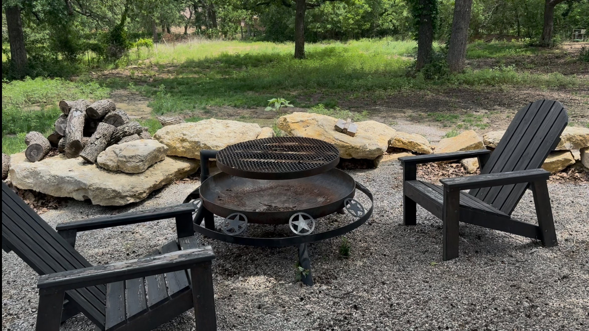 Close-up view of a campfire pit with chairs arranged around it in a wooded area