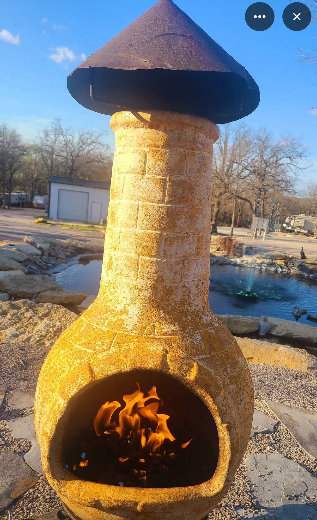 Close-up view of a fire pit with glowing embers outside a cabin at dusk