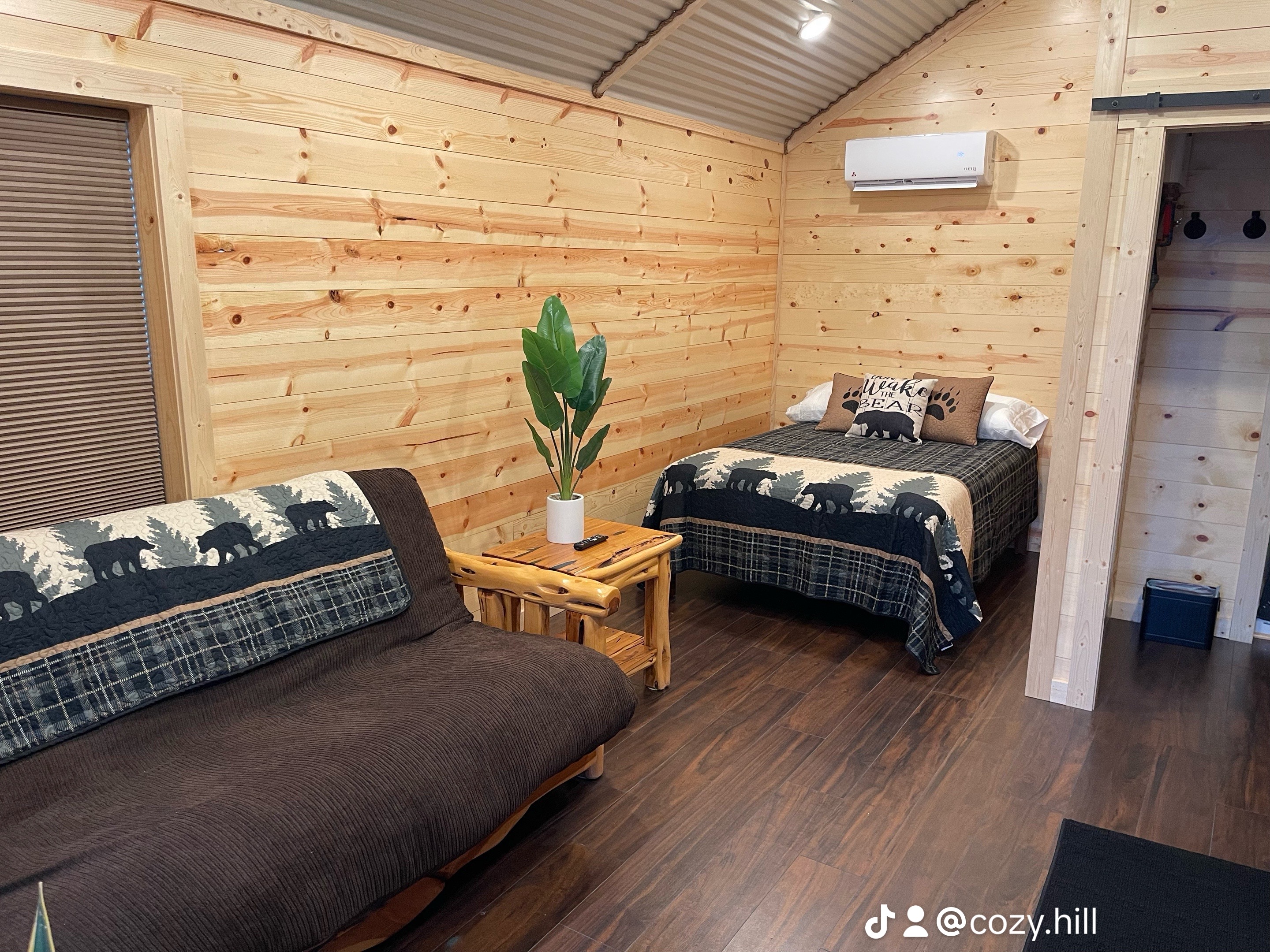 Eye-level view of a cozy cabin living room with wooden walls and large windows