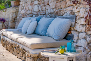 Outdoor seating with blue cushions beside a traditional stone wall at the Mallorca finca
