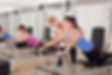 Instructor assisting a client during a group Pilates class on equipment at Encore Pilates in Gainesville, FL. Providing expert guidance to improve strength, flexibility, and core stability in a supportive studio environment.