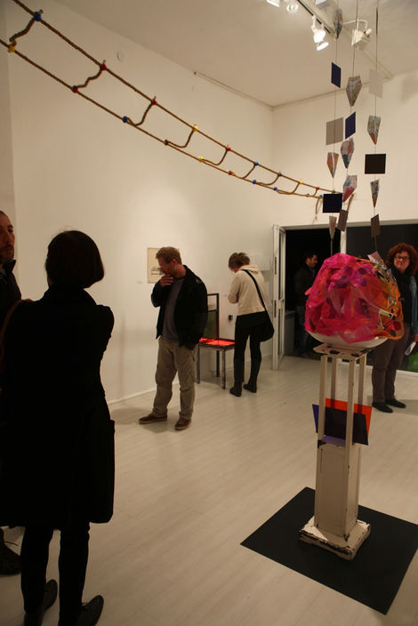 Gallery visitors facing a large sculptural structure resembling a bouquet or flowering form