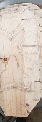 Wooden board with design sketches, circular saw blade base, woodworking project details.