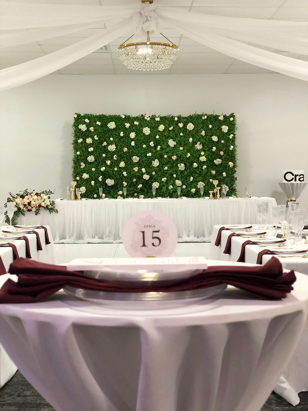 Perfectly aligned photo with table number in foreground with tables on either side and hedge backdrop in background.