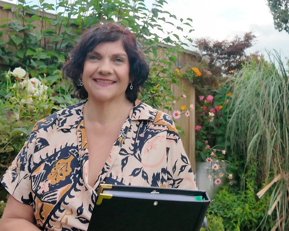 A celebrant joyfully prepares for a ceremony, holding a binder, surrounded by a lush garden setting.